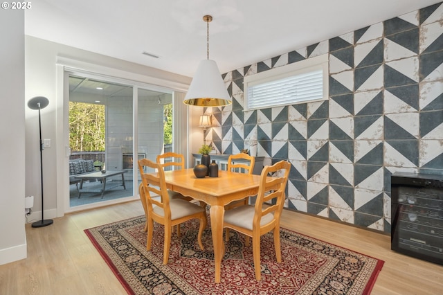 dining room featuring baseboards, visible vents, light wood finished floors, and wine cooler