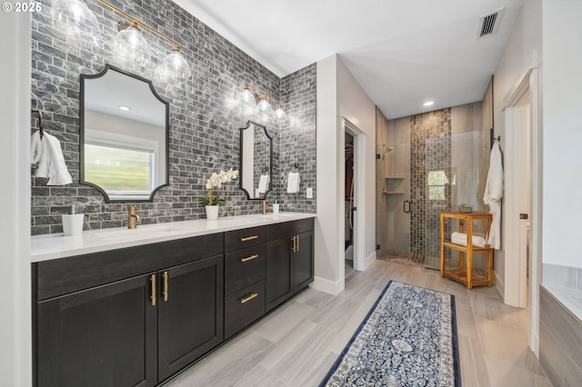 full bathroom with a wealth of natural light, a sink, double vanity, visible vents, and a shower stall
