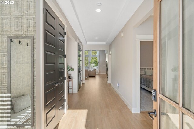 hallway featuring light wood finished floors, baseboards, and recessed lighting