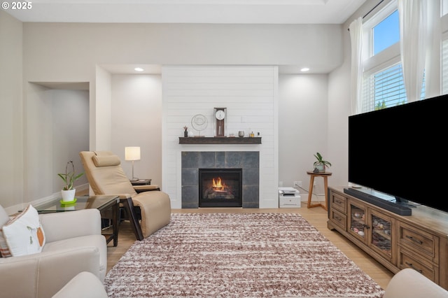 living area featuring recessed lighting, light wood finished floors, and a tiled fireplace