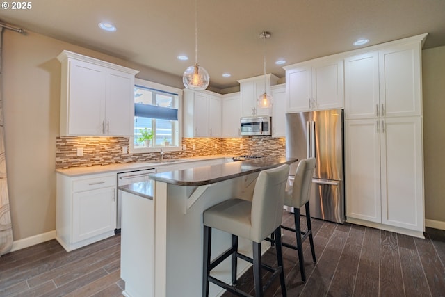 11201 NE 127th Ave, Vancouver, WA 98682 - kitchen with appliances with stainless steel finishes, dark wood-style flooring, white cabinets, a breakfast bar area, and backsplash
