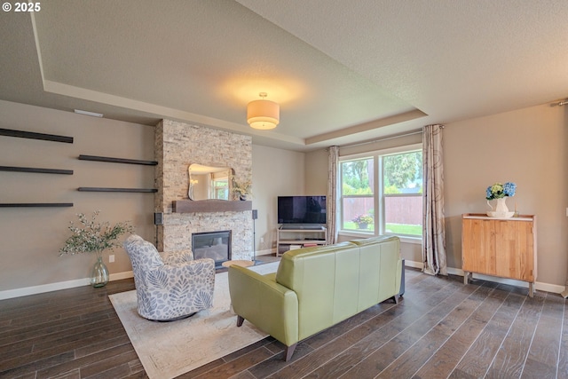 11201 NE 127th Ave, Vancouver, WA 98682 - living area featuring a tray ceiling, dark wood-style flooring, a stone fireplace, baseboards, and a textured ceiling