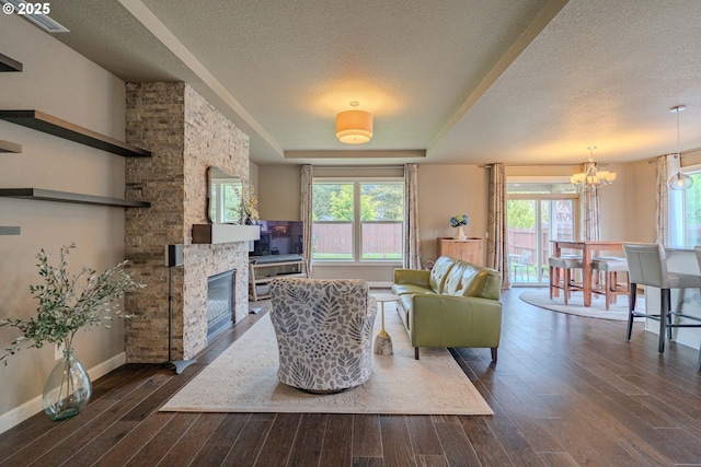 11201 NE 127th Ave, Vancouver, WA 98682 - living area with a stone fireplace, dark wood-style flooring, a chandelier, a textured ceiling, and baseboards