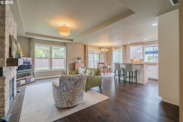 11201 NE 127th Ave, Vancouver, WA 98682 - living room featuring a textured ceiling, dark wood finished floors, a chandelier, a tray ceiling, and baseboards