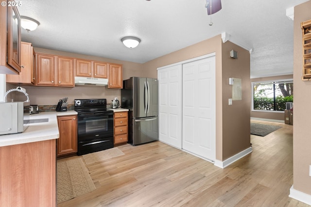 kitchen featuring electric range, freestanding refrigerator, under cabinet range hood, light countertops, and light wood finished floors