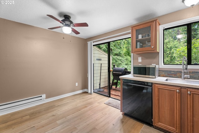 kitchen with black dishwasher, stainless steel microwave, a sink, a baseboard radiator, and light countertops