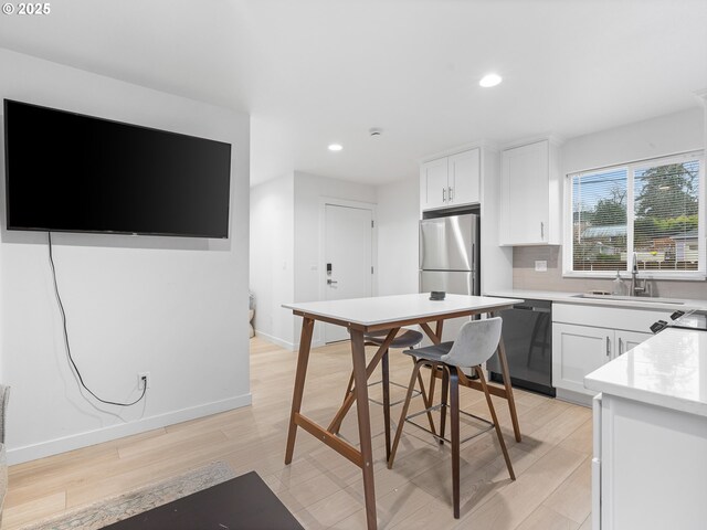 kitchen with black dishwasher, sink, white cabinets, electric range, and light wood-type flooring