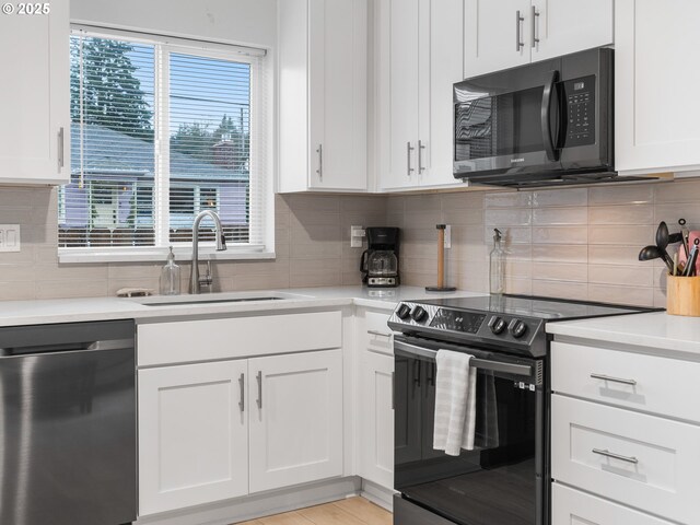 kitchen featuring white cabinetry, light hardwood / wood-style flooring, backsplash, and black appliances