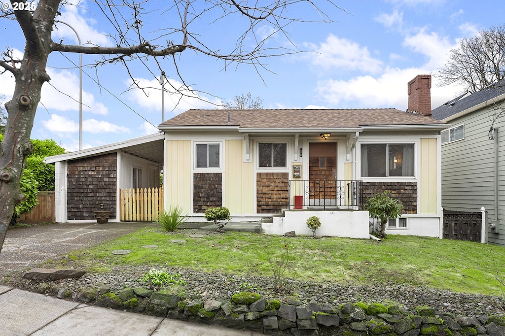 view of front facade with driveway, a front lawn, a chimney, and fence