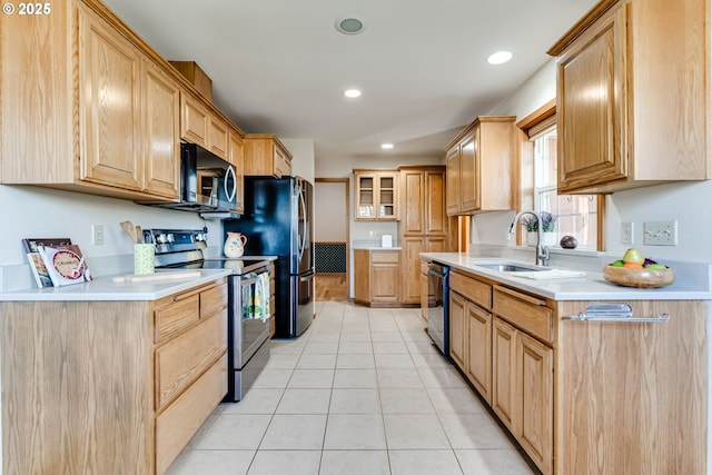 kitchen featuring a sink, stainless steel appliances, light countertops, and glass insert cabinets