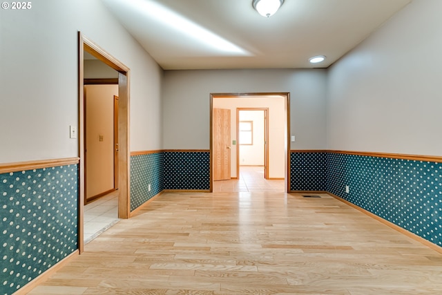 spare room with a wainscoted wall and light wood-style floors