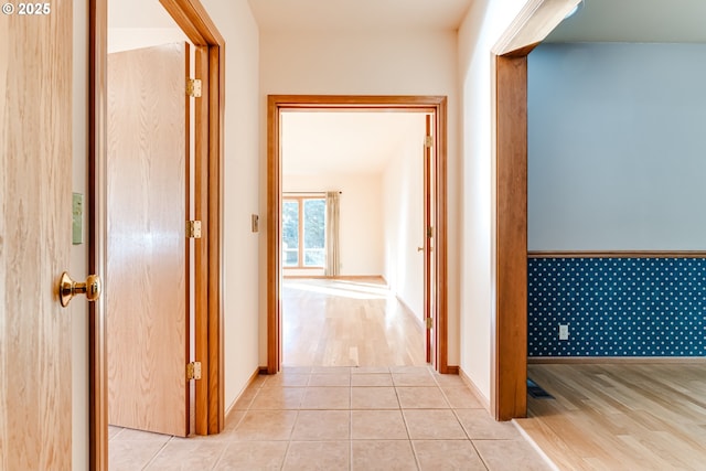 corridor with light tile patterned floors and baseboards