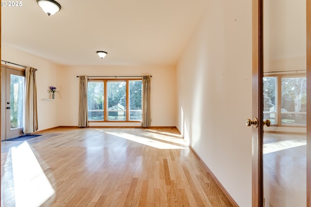 unfurnished room featuring light wood-style floors, baseboards, and french doors