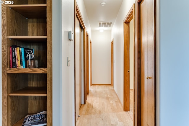 hallway featuring light wood-type flooring, visible vents, and baseboards