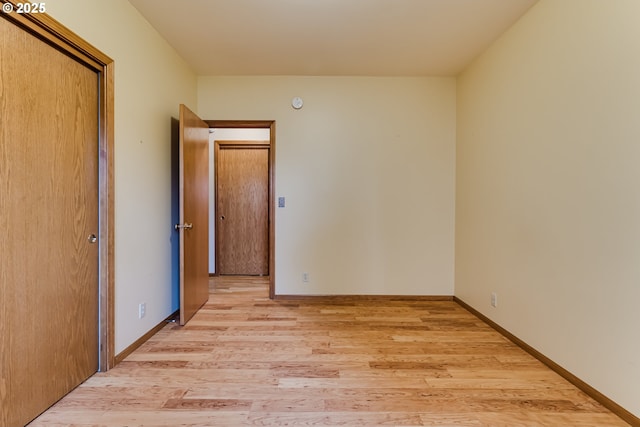 spare room with baseboards and light wood-style floors