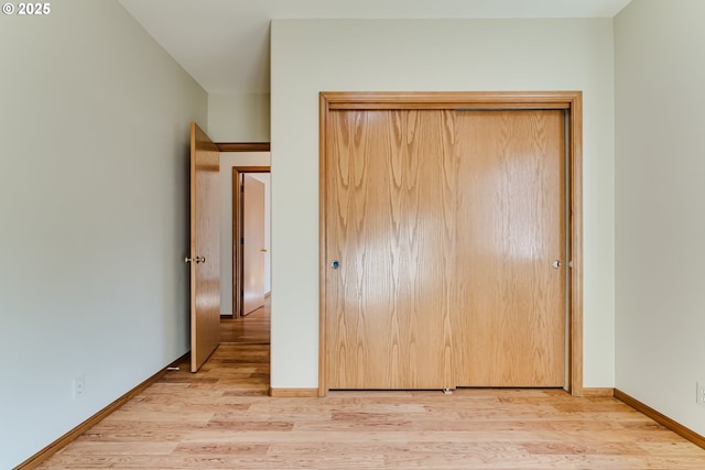 unfurnished bedroom with a closet, light wood-type flooring, and baseboards