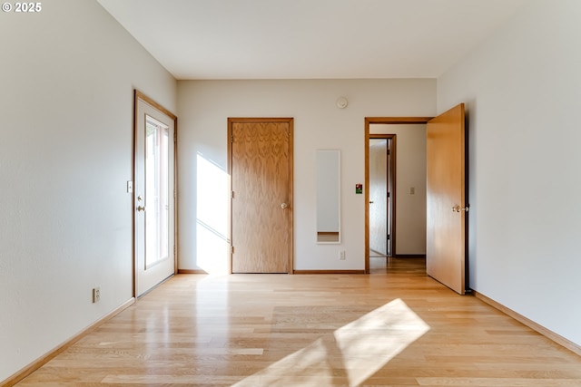 unfurnished bedroom featuring light wood-style floors, multiple windows, and baseboards