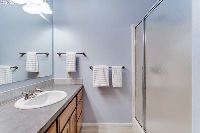 full bathroom featuring a stall shower, vanity, baseboards, and tile patterned floors