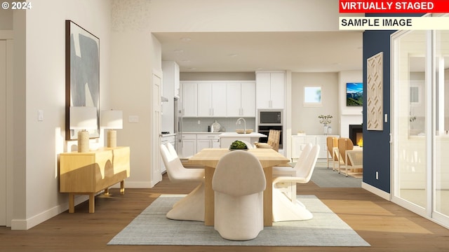 dining area with light wood-style flooring, a fireplace, and baseboards