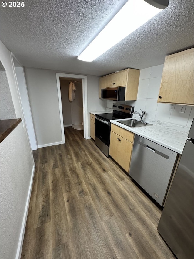 kitchen featuring a textured ceiling, dark wood-type flooring, stainless steel appliances, sink, and backsplash