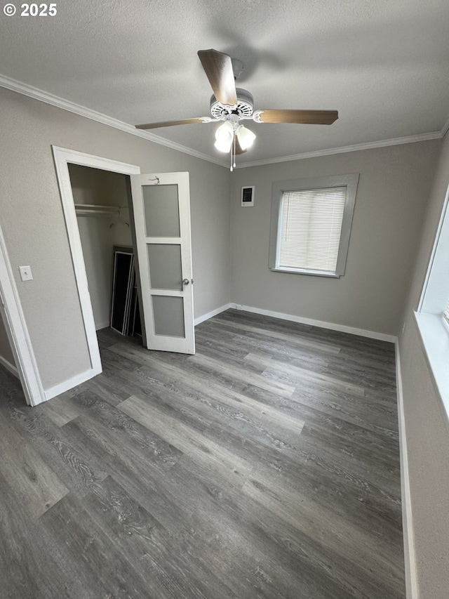 unfurnished bedroom featuring a textured ceiling, a closet, ornamental molding, dark wood-type flooring, and ceiling fan