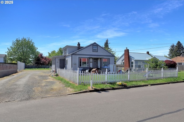 bungalow-style house with a fenced front yard and driveway