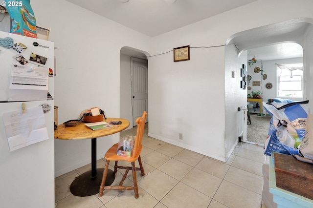 dining room with light tile patterned floors, arched walkways, and baseboards