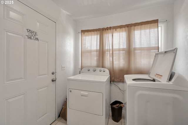 clothes washing area with laundry area, plenty of natural light, washing machine and dryer, and light tile patterned floors