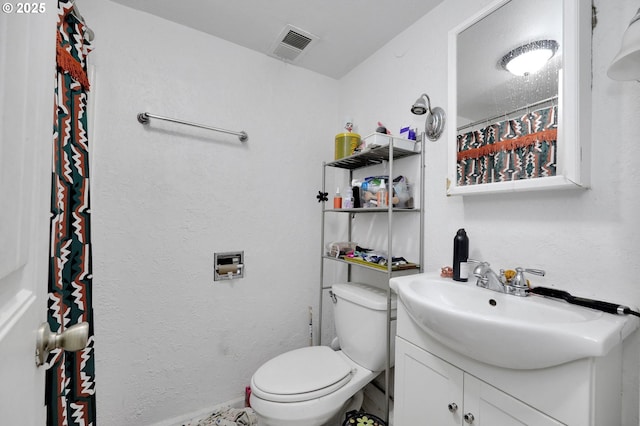 bathroom featuring vanity, toilet, and visible vents
