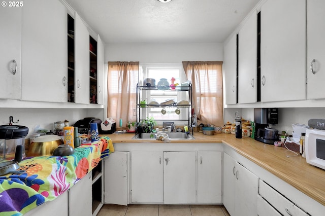 kitchen featuring a sink, light countertops, white cabinets, and white microwave