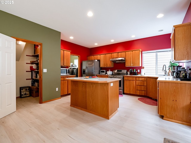 kitchen with a center island, under cabinet range hood, brown cabinetry, stainless steel appliances, and light wood finished floors