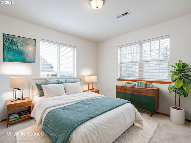 carpeted bedroom with visible vents, multiple windows, and baseboards