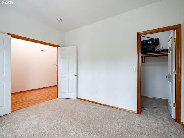 unfurnished bedroom with a spacious closet, carpet flooring, a closet, and baseboards