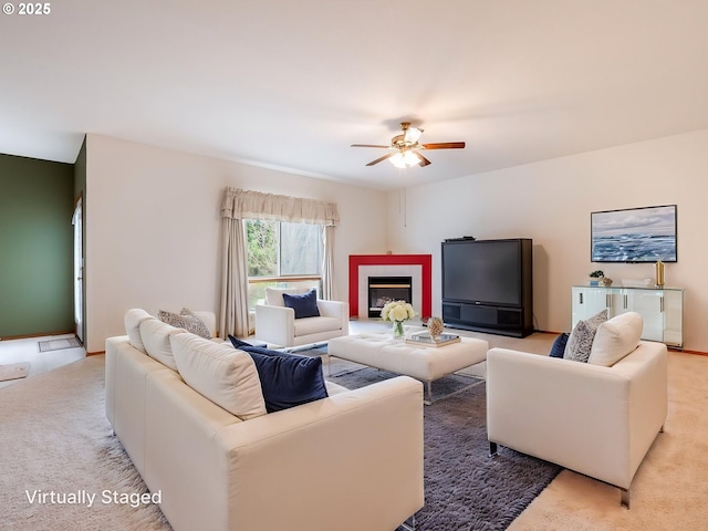 carpeted living room featuring a ceiling fan and a fireplace