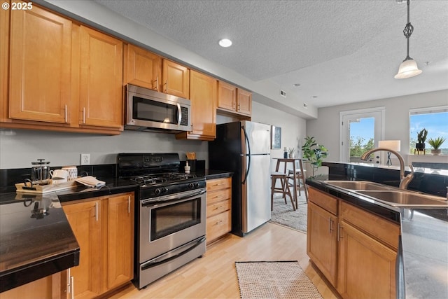 9183 NW Germantown Rd, Portland, OR 97231 - kitchen featuring stainless steel appliances, a sink, light wood finished floors, dark countertops, and a textured ceiling