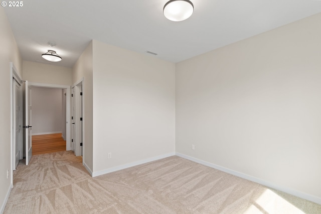 carpeted empty room featuring baseboards and visible vents