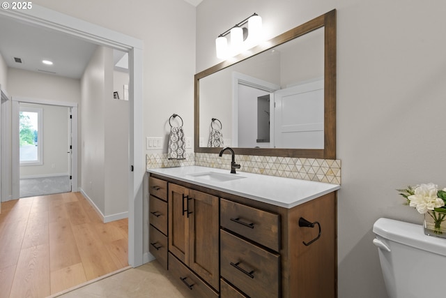 half bath featuring decorative backsplash, visible vents, toilet, and vanity