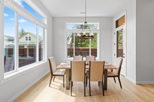 dining room featuring baseboards, a notable chandelier, and light wood-style flooring