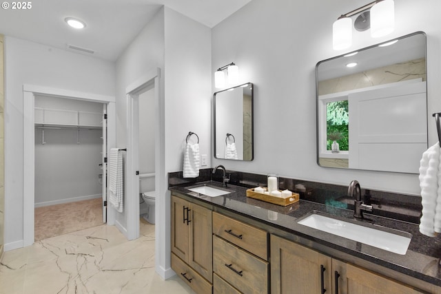 full bath with marble finish floor, a sink, toilet, and double vanity