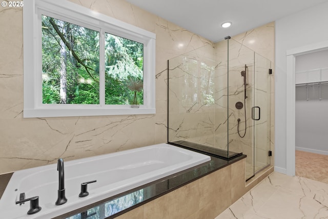 bathroom with marble finish floor, a marble finish shower, a garden tub, and a spacious closet