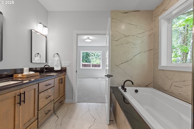 bathroom featuring marble finish floor, a sink, a garden tub, and double vanity