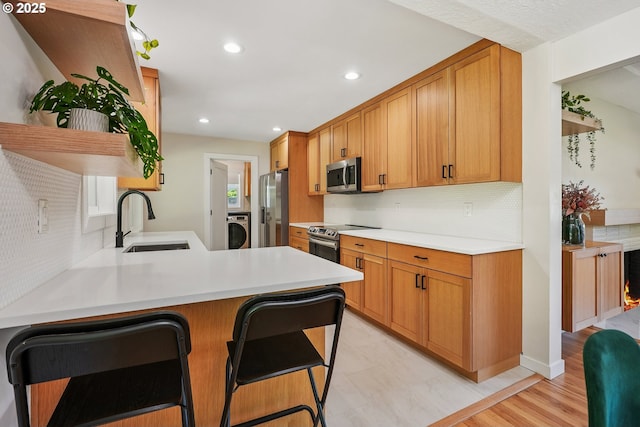 10559 NE Thompson St, Portland, OR 97220 - kitchen featuring stainless steel appliances, a sink, washer / clothes dryer, backsplash, and light countertops