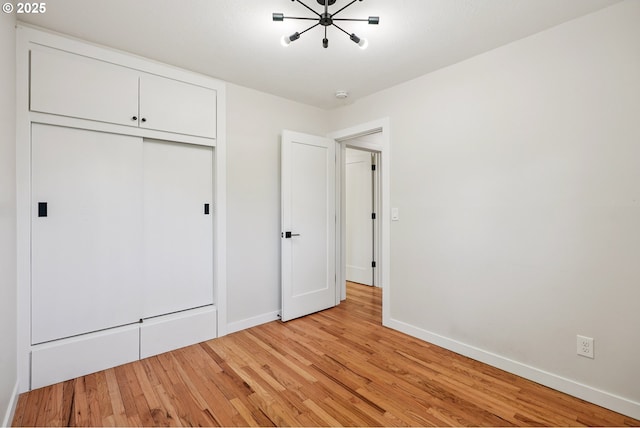 10559 NE Thompson St, Portland, OR 97220 - unfurnished bedroom with light wood-style flooring, baseboards, a closet, and a chandelier