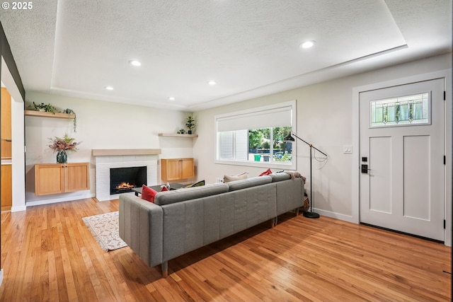 10559 NE Thompson St, Portland, OR 97220 - living room featuring light wood-type flooring, a textured ceiling, a fireplace, baseboards, and recessed lighting