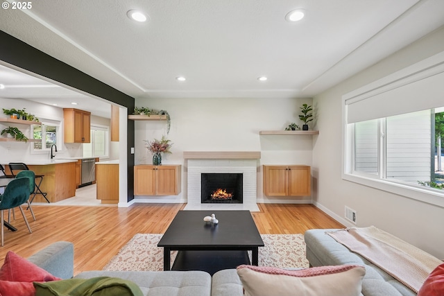 10559 NE Thompson St, Portland, OR 97220 - living area with recessed lighting, light wood-style flooring, a brick fireplace, and baseboards
