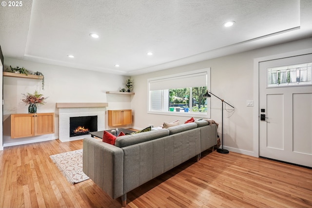 10559 NE Thompson St, Portland, OR 97220 - living room with light wood-style floors, a fireplace, baseboards, recessed lighting, and a textured ceiling