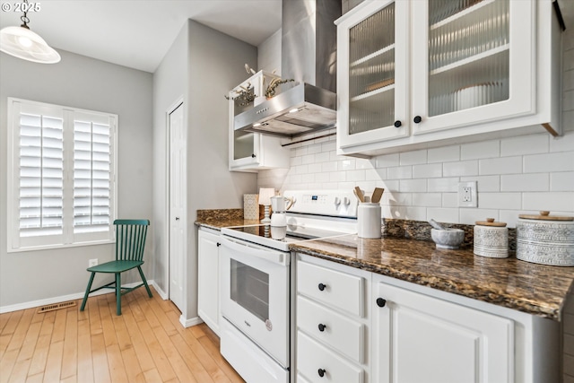 kitchen featuring decorative backsplash, white cabinets, white electric stove, and wall chimney exhaust hood