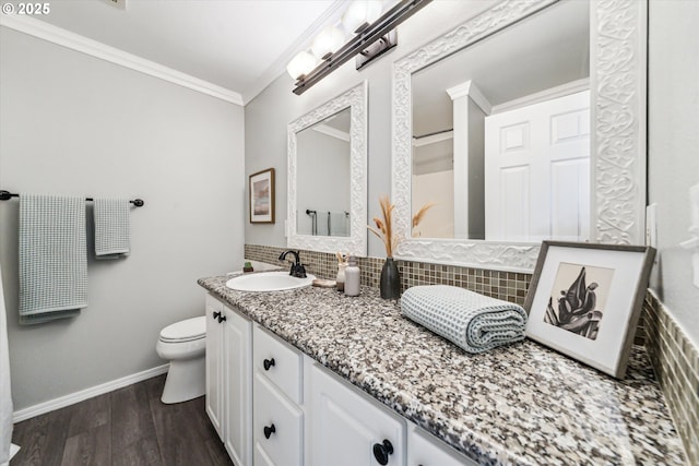 bathroom featuring crown molding, backsplash, vanity, wood finished floors, and baseboards