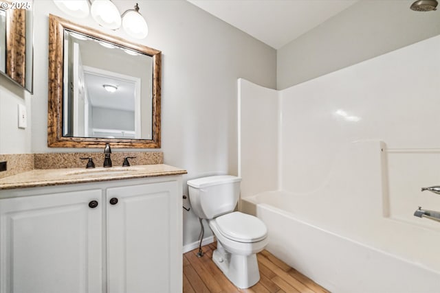 full bath with baseboards, toilet, wood finished floors, tub / shower combination, and vanity