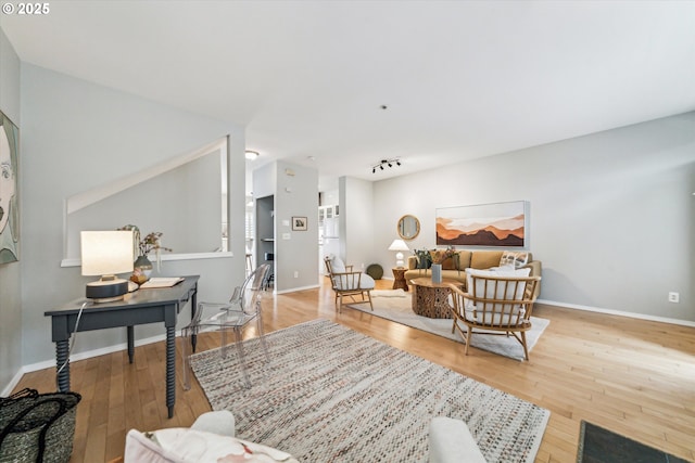 living area featuring track lighting, baseboards, and hardwood / wood-style floors